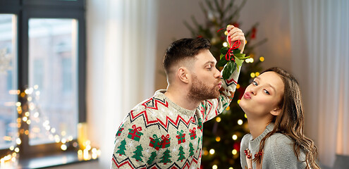 Image showing happy couple kissing under mistletoe on christmas