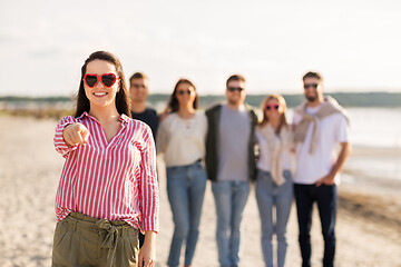 Image showing woman with friends on beach pointing to you