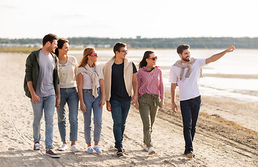 Image showing happy friends walking along summer beach