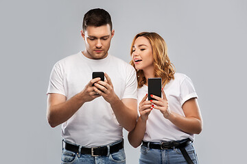 Image showing happy couple in white t-shirts with smartphones