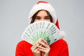 Image showing happy woman in santa hat with money on christmas