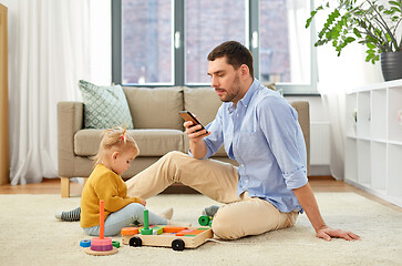 Image showing father with smartphone and baby daughter at home