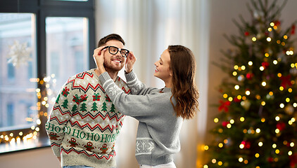 Image showing happy couple in ugly sweaters at home on christmas