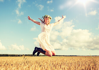 Image showing happy woman in wreath jumping on cereal field