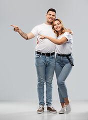 Image showing happy couple in white t-shirts pointing fingers