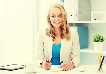 Image showing businesswoman writing to notebook at office