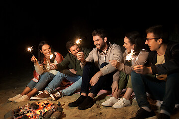 Image showing happy friends with sparklers at camp fire at night