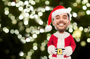 Image showing smiling man in santa costume over christmas tree