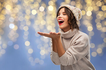 Image showing woman in winter hat sending air kiss on christmas