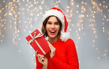 Image showing happy woman in santa hat with red christmas gift