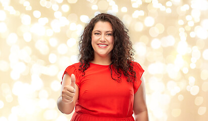 Image showing happy woman showing thumbs up over lights