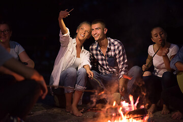 Image showing young friends relaxing around campfire