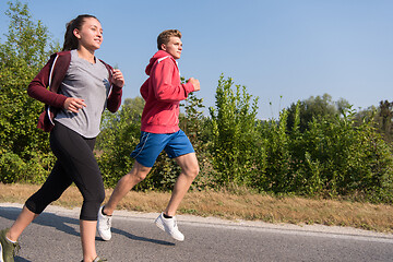 Image showing young couple jogging along a country road