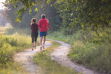 Image showing young couple jogging along a country road