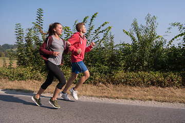 Image showing young couple jogging along a country road