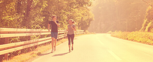 Image showing young couple jogging along a country road