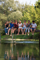 Image showing friends enjoying watermelon while sitting on the wooden bridge