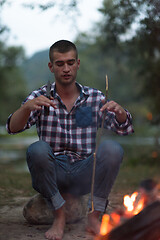 Image showing young friends relaxing around campfire