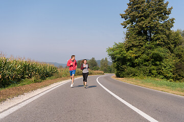 Image showing young couple jogging along a country road