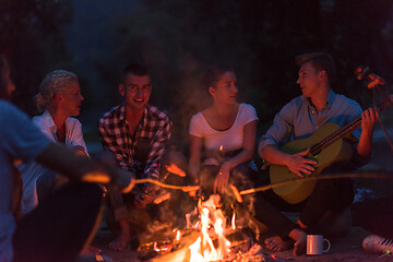 Image showing young friends relaxing around campfire