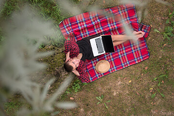 Image showing top view of man using a laptop computer under the tree