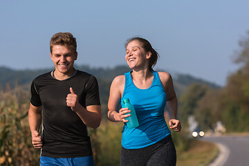 Image showing young couple jogging along a country road