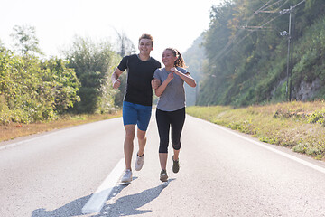 Image showing young couple jogging along a country road