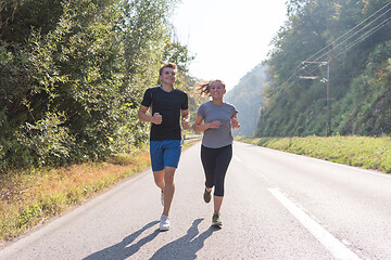 Image showing young couple jogging along a country road