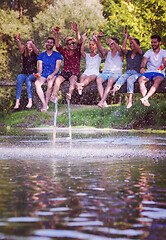 Image showing friends enjoying watermelon while sitting on the wooden bridge