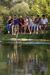 Image showing friends enjoying watermelon while sitting on the wooden bridge