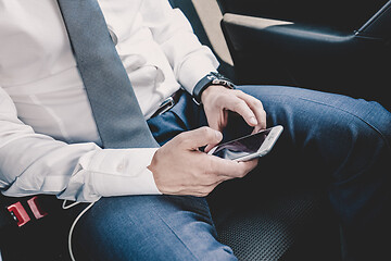 Image showing Close up of businessman using mobile smart phone in a car.