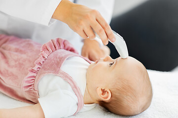 Image showing doctor with thermometer measures baby temperature