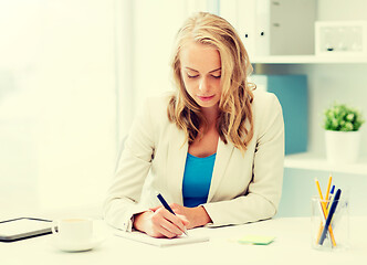 Image showing businesswoman writing to notebook at office