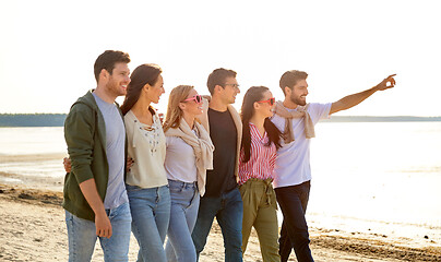 Image showing happy friends walking along summer beach