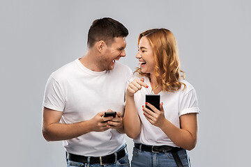 Image showing happy couple in white t-shirts with smartphones