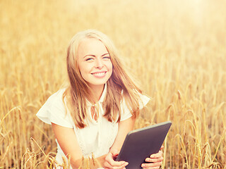 Image showing happy young woman with tablet pc on cereal field