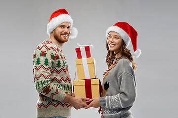 Image showing happy couple in christmas sweaters with gifts