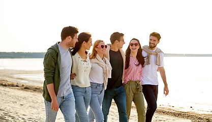 Image showing happy friends walking along summer beach