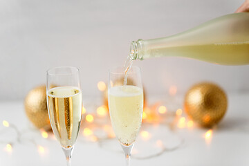 Image showing champagne pouring from bottle to christmas glasses