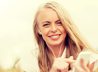 Image showing happy woman with smartphone and earphones