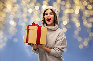 Image showing young woman in winter hat holding christmas gift