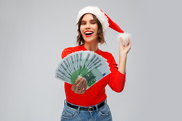 Image showing happy woman in santa hat with money on christmas