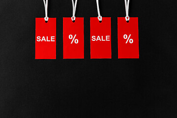 Image showing red tags with discount signs on black background