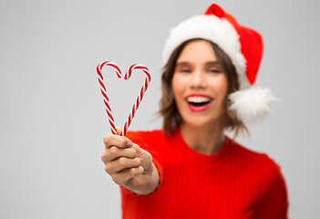 Image showing happy woman in santa hat showing candy canes