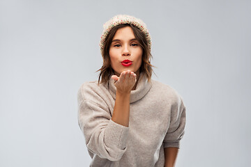 Image showing young woman in knitted winter hat sending air kiss