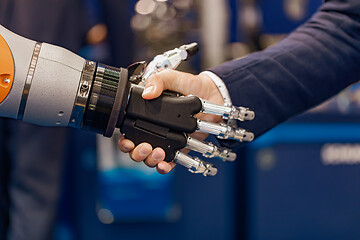 Image showing Hand of a businessman shaking hands with a Android robot.