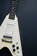 Image showing White V shape electric guitar on dark grunge background.