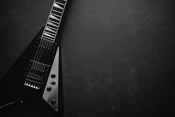 Image showing Black V shape electric guitar on dark grunge background.