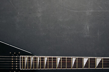 Image showing Black V shape electric guitar on dark grunge background.