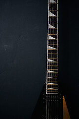 Image showing Black V shape electric guitar on dark grunge background.